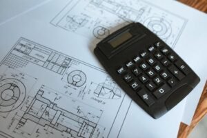 Close-up of a calculator resting on technical engineering blueprints, showcasing precise calculations.